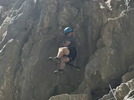 Climbing a via ferrata up a steep rock face.