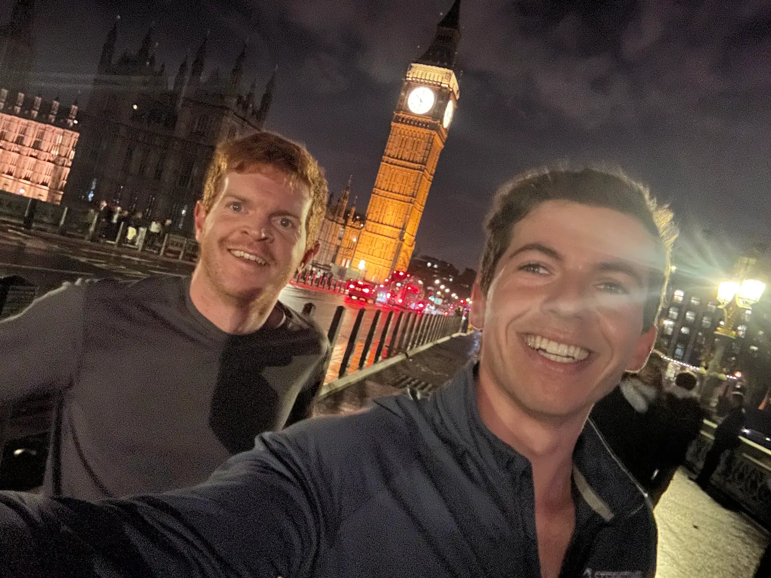Ben and Cam grinning on Westminster Bridge at night, with Big Ben lit up behind them.