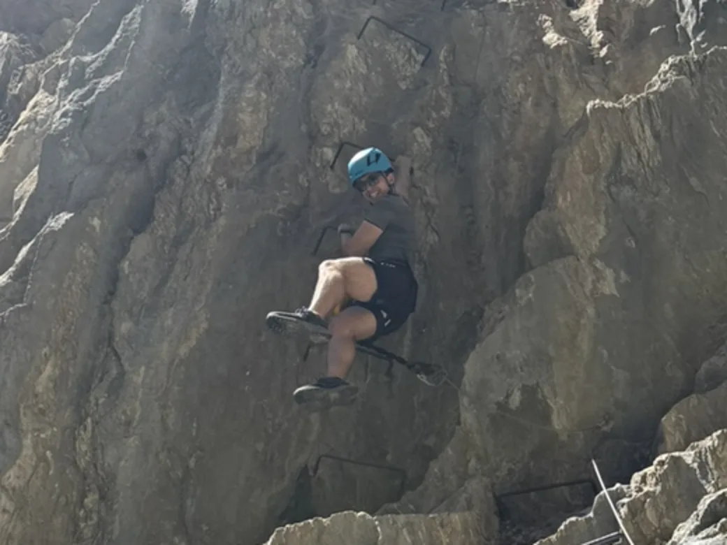 Climbing a via ferrata up a steep rock face.