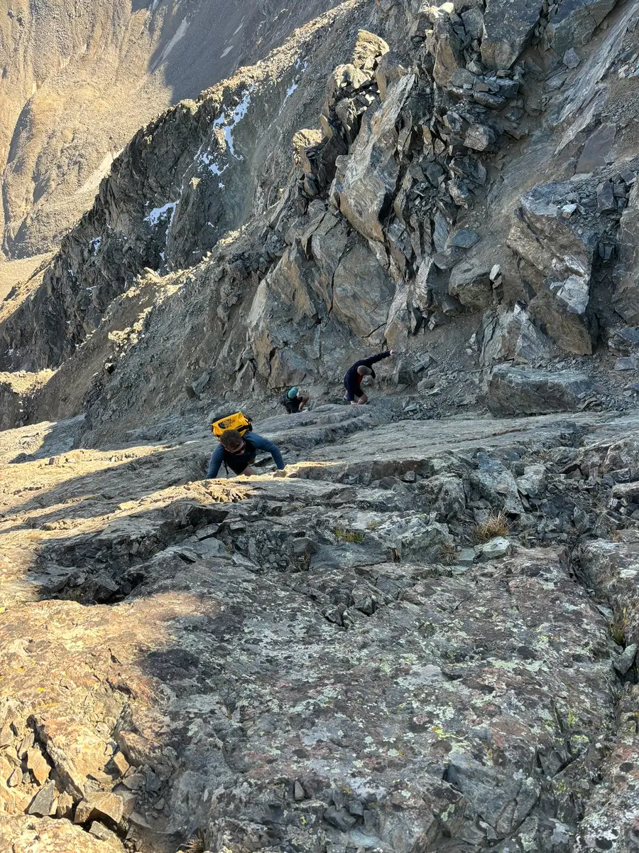 Hikers scrambling up a rocky ridge in Colorado.